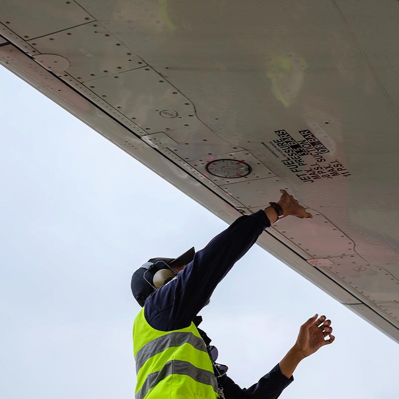 Person checking under plane wing